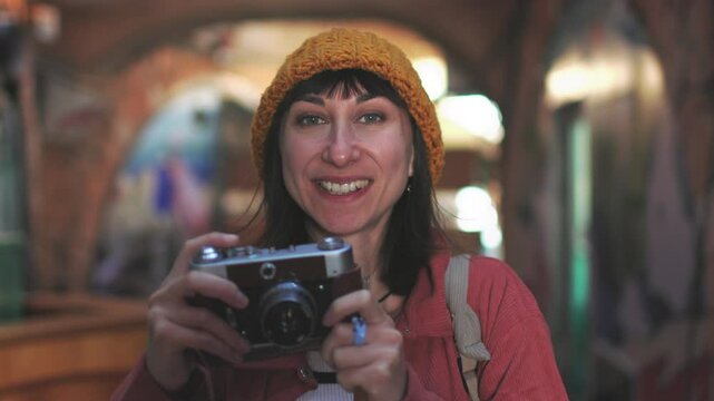 Young beautiful smiling hipster woman in fashionable clothes with camera. Carefree woman with backpack taking picture with her camera. tourist with camera.