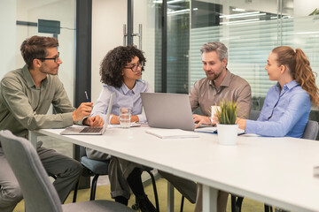Happy four business people executive team working at laptop having discussion at office meeting showing financial project