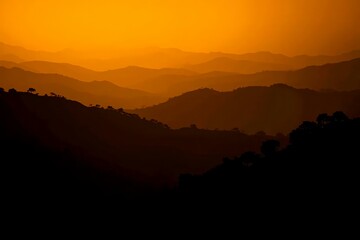 Fototapeta premium Serene Silhouette of Mountain Ranges Against an Orange Sunset Sky