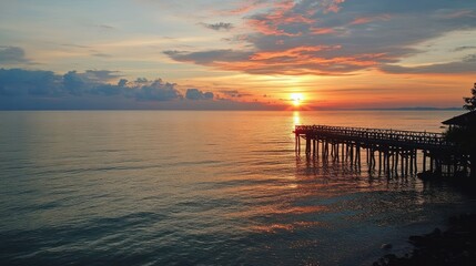 Obraz premium Coastal sunset pier; tranquil ocean, vibrant sky