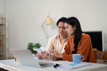 Couples' financial planning. Engaged couple discussing their finances at home, looking concerned and focused on their budget.