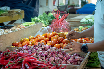 Activities in the vegetable and spice trader stand (red chilli, onion, garlic, tomat, cayenne pepper, potato) in Jambu Dua traditional market, traders serve buyers who come to buy these vegetables