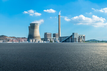 Asphalt road leading to power plant with blue sky and white clouds