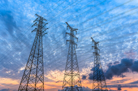 High voltage power lines against a dramatic sky at sunset