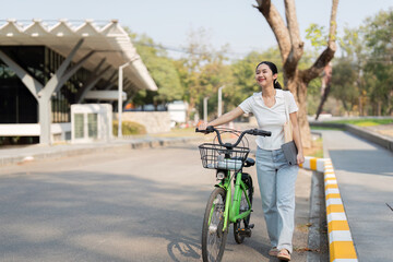 Obraz premium Young woman walking her bicycle while enjoying the outdoors, radiating positivity and sustainability.