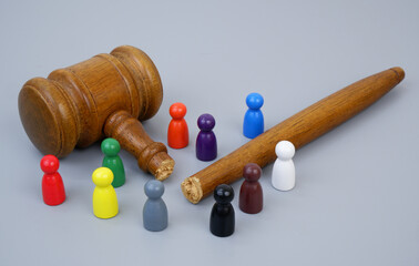 Wooden colored figures of people and broken judge gavel on gray background.