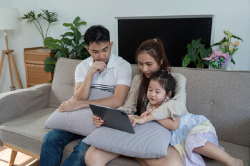 Obraz premium Family enjoying time together on a couch, exploring a tablet with joy and laughter.