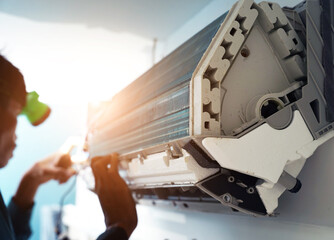 The worker cleans and repairs the air conditioner to ensure it operates properly