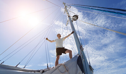 Male captain stands proudly on a sailboat enjoying the moment