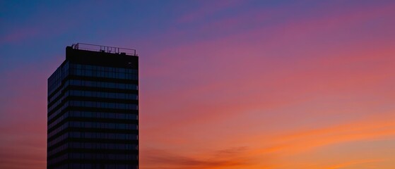 Obraz premium Modern Office Building Silhouette Against Sunset Sky 