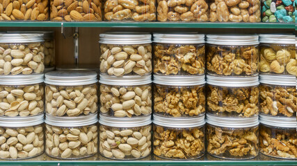 Assorted nuts in glass jars: almonds, walnuts, pistachios, and cashews displayed on shelves