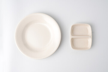 Empty beige colored round shaped plate and dual dipping bowl. Isolated on white background. Flat Lay Setup