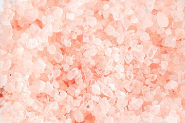 Pink colored Himalayan coarse salt (halite) scattered on the table. Isolated on white background.