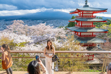 Fujiyoshida, Yamanashi Prefecture, Japan - April 17, 2024: Arakura Fuji Asone Shrine with tourists. Mount Fuji with red pagoda during cherry blossom season.