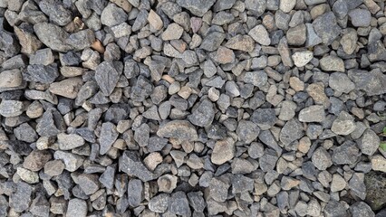 A high-angle shot reveals a textured expanse of small, irregularly shaped gravel stones, creating a natural, abstract pattern