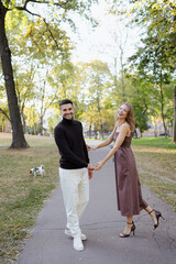 Obraz premium Couple Enjoying a Playful Moment in the Park With a Dog on a Sunny Day