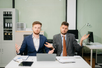 Two office colleagues discuss ideas for a startup project in a modern workspace, using laptops and smartphones