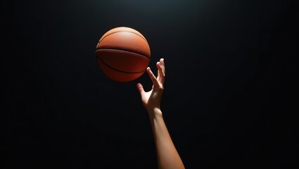 A basketball player gracefully releases the ball into the air, aiming confidently, under dramatic lighting against a dark background, capturing the precision, motion, and energy of the game.
