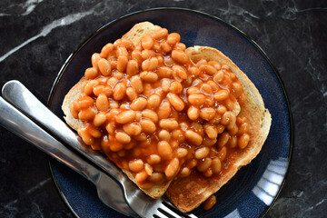 Beans on toast with fork and knife on a plate