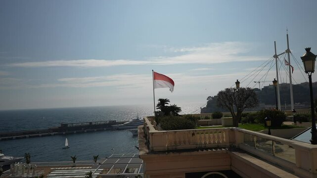 Monte Carlo harbour panorama with national flag of Monaco waving in the wind