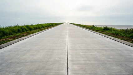 Fototapeta premium Expansive Concrete Road Cutting Through Lush Green Landscape Under Cloudy Sky