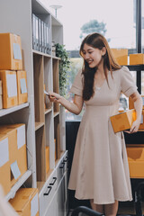 Asian SME business women use laptop computer checking customer order online shipping boxes at home....