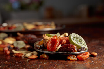 Dried tropical fruits, nuts, and raisins on a kitchen table.