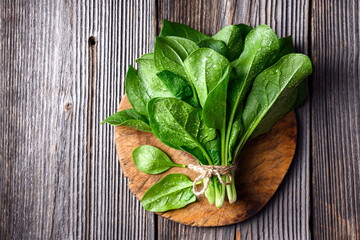 Top view of fresh green spinach leaves with water drops on rustic wooden table. Organic spinach...