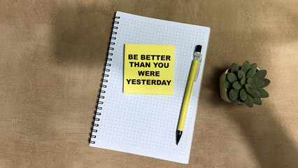 Concept of Be Better Than You Were Yesterday write on sticky notes isolated on Wooden Table.