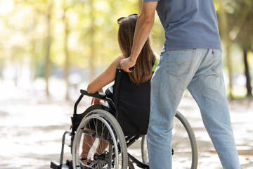 Obraz premium Man pushing woman in wheelchair in park: assistance and mobility