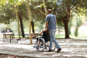 Nurse pushing senior woman in wheelchair in park