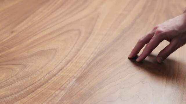 Slow motion man hand touches black walnut dining table surface