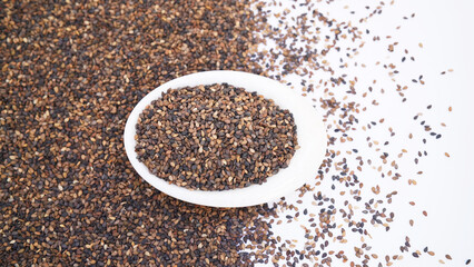 close-Up of Organic Black Sesame seeds(Sesamum indicum) or Black Til with shell in a white ceramic bowl with the gradient background of whole Black Sesame seeds. Top view