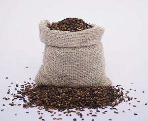 Close-up of organic Black Sesame (Sesamum indicum) Seeds in a jute bag on a heap of Black Sesame...