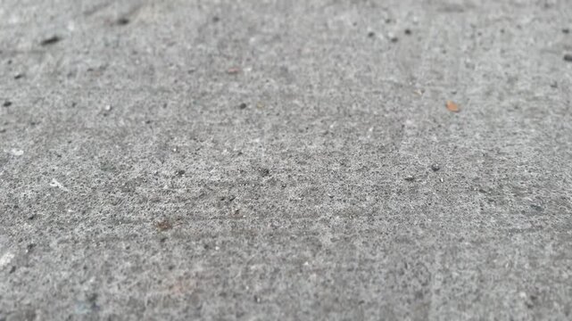 Close-up of rough asphalt road surface with small stones, cracks, and natural imperfections for a textured view.
