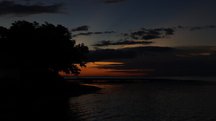 Low orange sunset in dramatic clouds over ocean in Indonesia