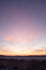 Serene winter sunrise over a frosty rural field in Ukraine with pastel-colored clouds and a vast open sky