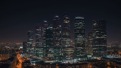 Obraz premium Modern skyscrapers illuminate Moscow's skyline at night, showcasing urban development and contemporary architecture