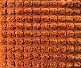 Close up of orange fabric in square checkerboard or checkered pattern. 3D checkerboard orange tufted fabric suitable for upholstery, carpet, or soft seating. Seamless background texture.