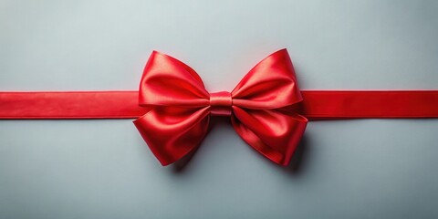 A vibrant red satin ribbon tied into a symmetrical bow on a light grey background, representing celebration and gifting.