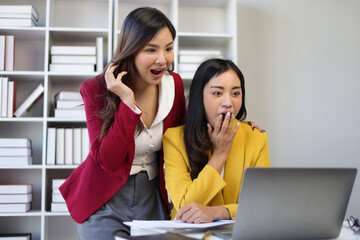 Two excited and surprised women looking at laptop. Employees and female co-workers are excited and happy about their promotions and bonuses while looking at their laptop.