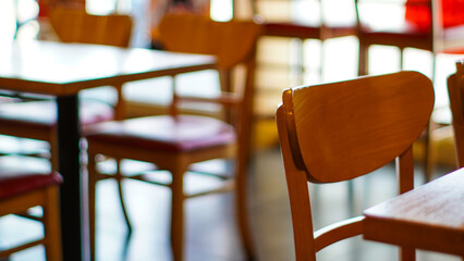 Close-up of a wooden chair in a restaurant with soft lighting, emphasizing the cozy dining ambiance.
