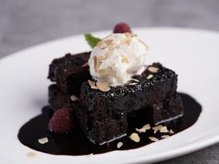 Decadent chocolate brownie drizzled with rich chocolate sauce, topped with a scoop of vanilla ice cream and sprinkled with toasted almond flakes