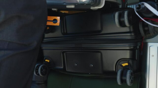 Person unloading suitcases in open van trunk, capacious automobile trunk full of baggage, preparation for departure on parking lot