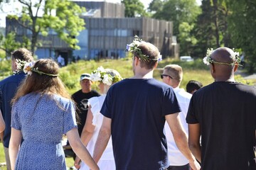 Naklejka premium Midsummer festival in Sweden.Different people with wreaths on their heads dance together on midsummer