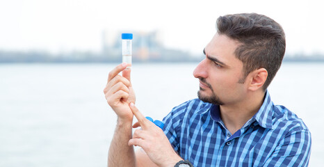 Man ecologist studies water samples taken from a reservoir. Student, practical work.