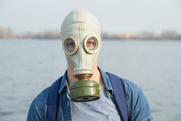 Young man in a gas mask on a summer day. Air pollution by carbon monoxide emissions. Breathe...
