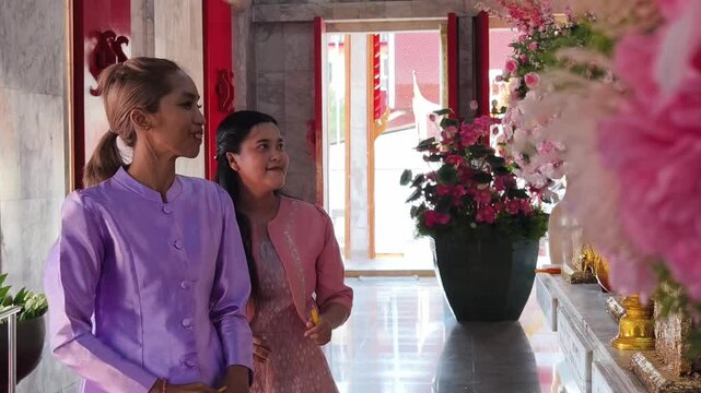 Two Thai women spend time in the tranquil setting of a Buddhist temple