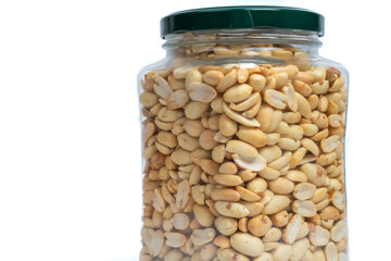 Glass jar with green lid filled with peanuts on isolated white background. Close up of snack peanut filled jar. Nutrition, storage, health and vegetarian concept. Copy space
