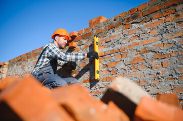 construction mason worker bricklayer installing red brick with trowel putty knife outdoors